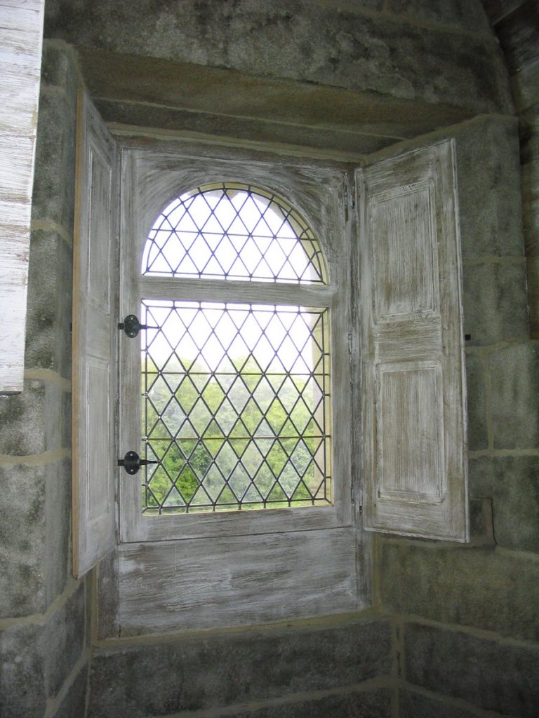 fenêtre de manoir avec vitraux et volets intérieurs